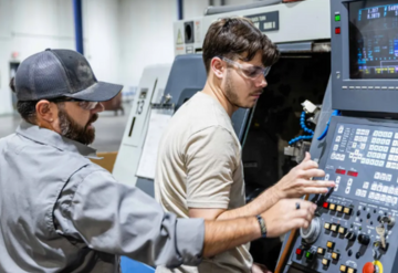 Two individuals at a manufacturing machine